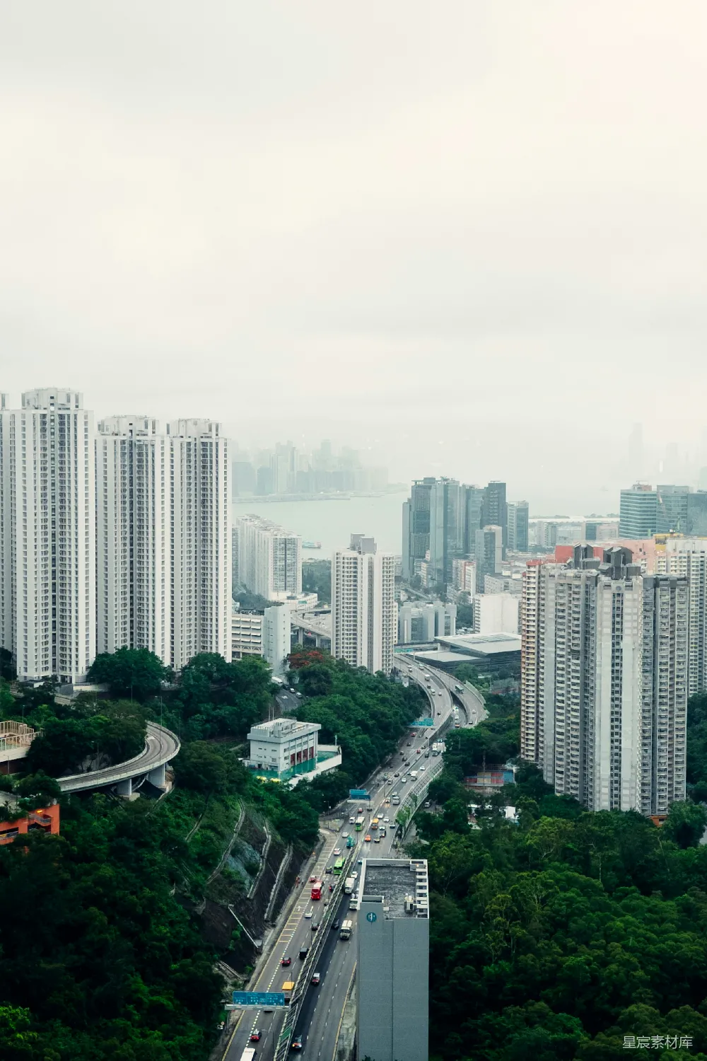 城市风景，高耸的建筑物，繁忙的高速公路和绿色的山丘。