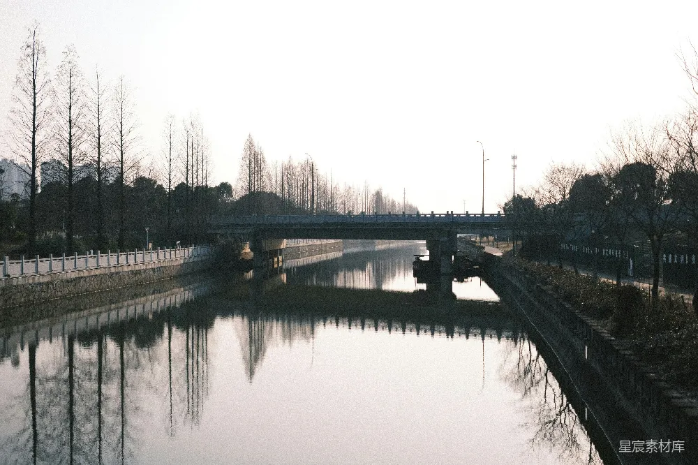 一座桥梁横跨着一条平静的河流，河面上映照着倒影。