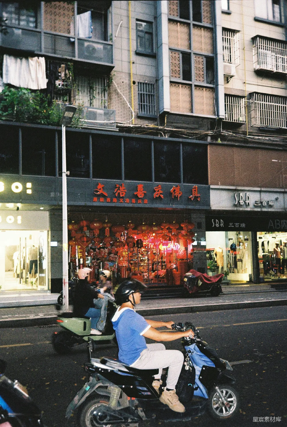 高清摄影 电影 一个男人骑着摩托车沿着街道行驶，旁边是高楼大厦。