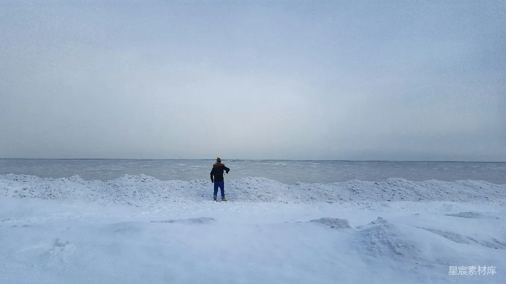 黑夹克的人在白天雪覆盖的田野上行走。