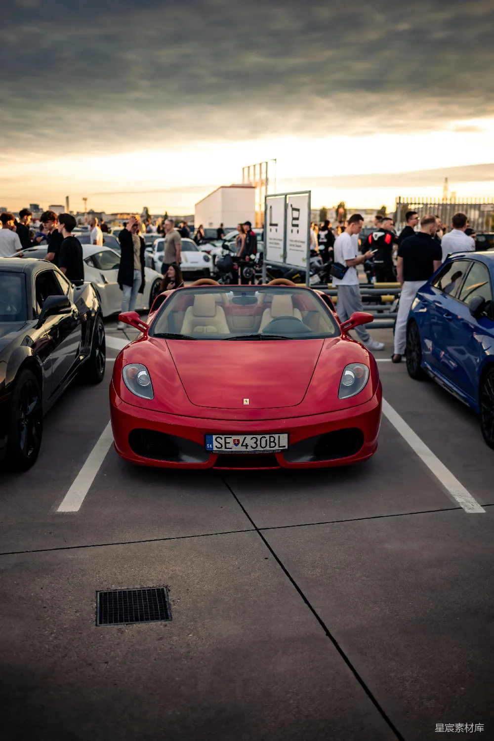 红 Ferrari 在日落时和其他汽车一起停着。