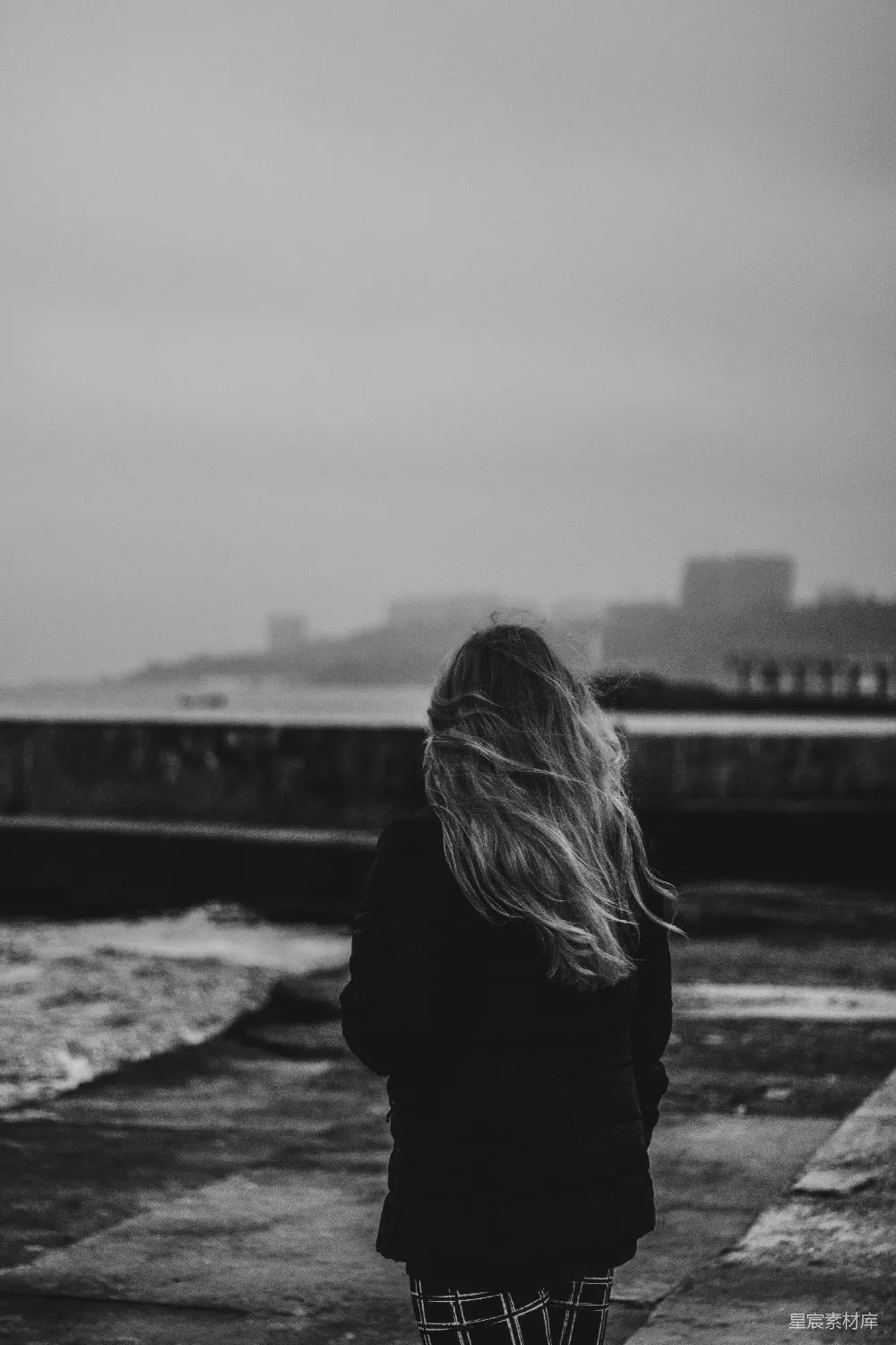 高清摄影  黑白照片中的女人穿着黑色夹克站在岩石上。