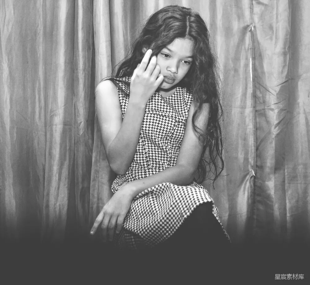 高清摄影  一个年轻女孩坐在椅子上，手里拿着一部手机。