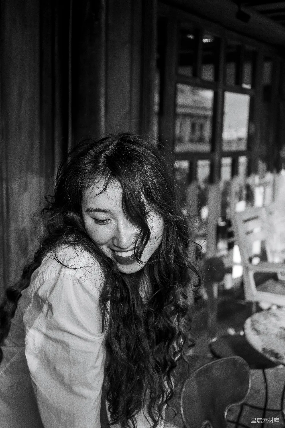 高清摄影  一个女人坐在桌子旁，脸上带着微笑。