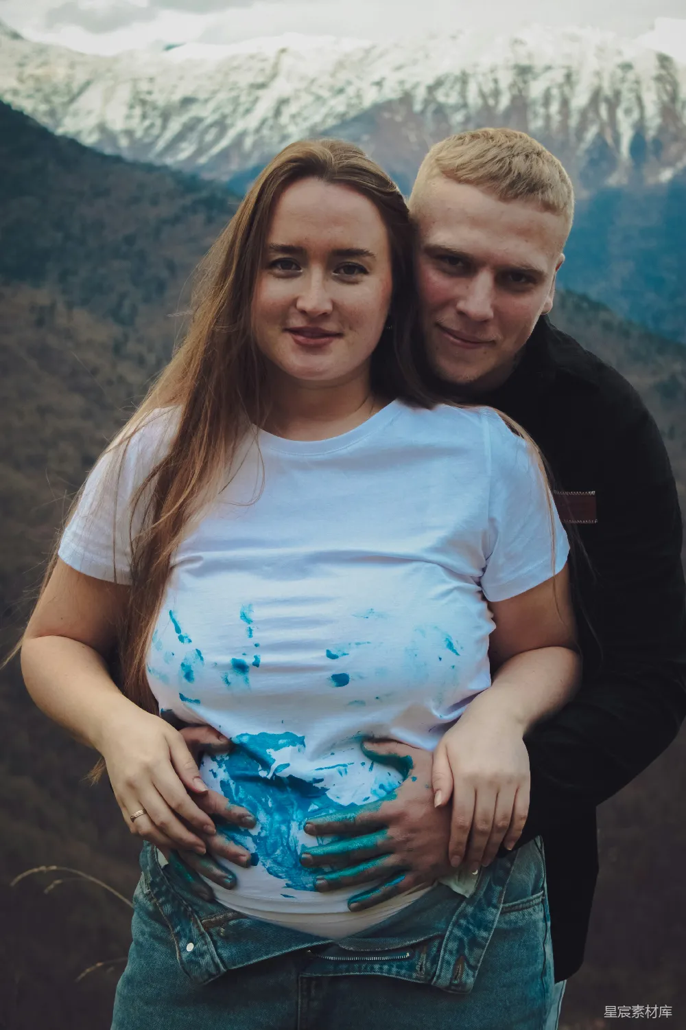 一个男人和一个女人并排站在背景中的山峰旁边。