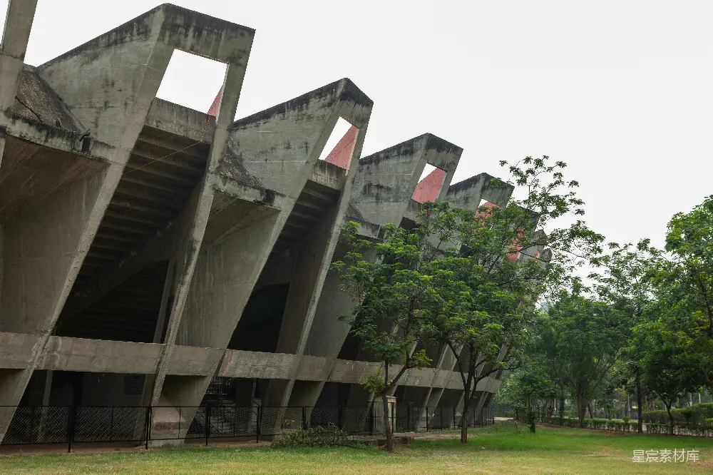 一座大型混凝土建筑紧邻一片郁郁葱葱的公园。