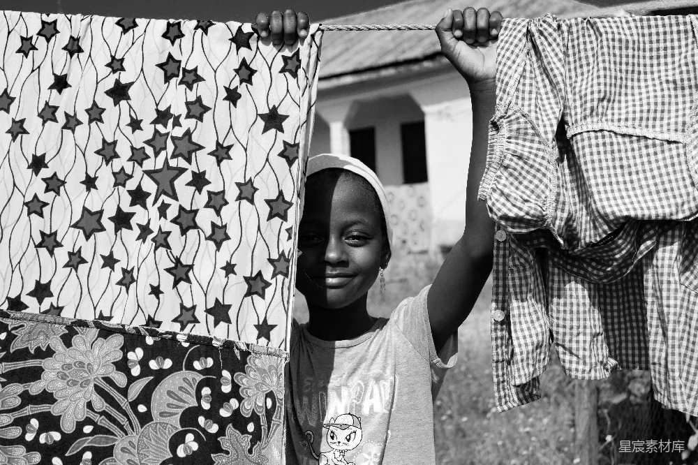 高清摄影  灰度照片中的男孩戴着帽子，手里拿着带衣服的衣架绳子。