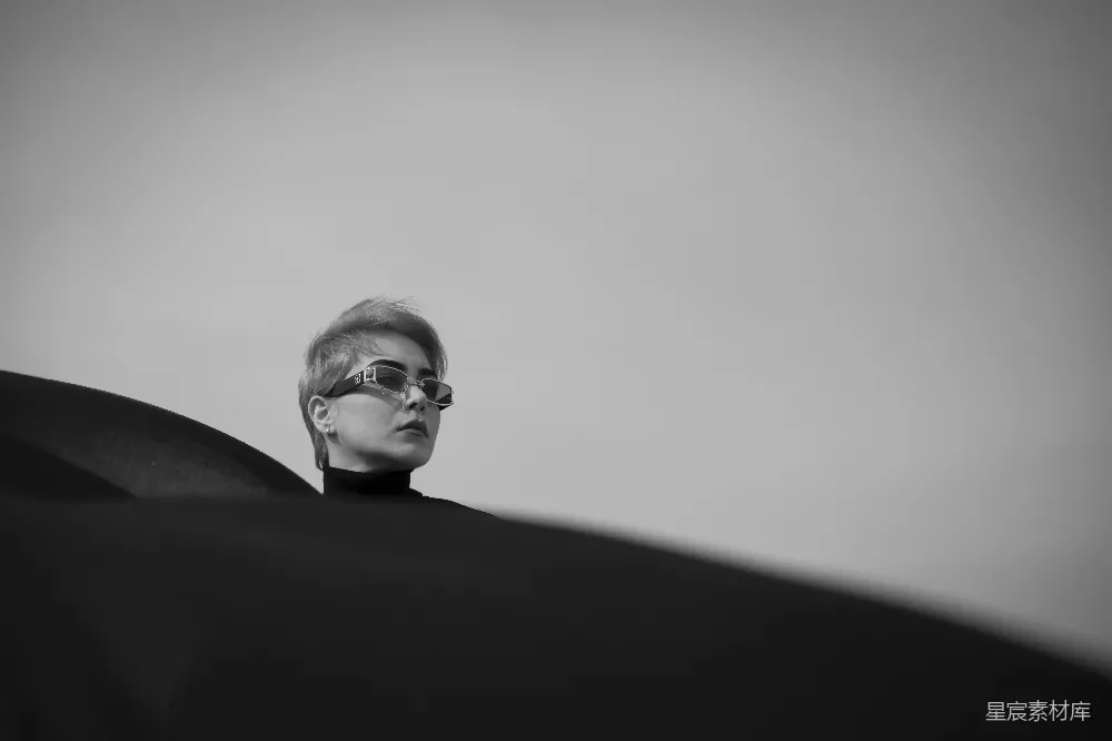 高清摄影  戴眼镜的女人站在一个黑色物体前面。