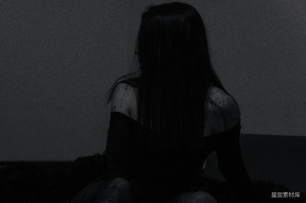 高清摄影  一个女人坐在昏暗房间的地板上。