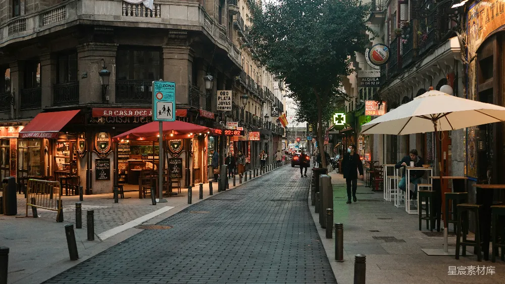 白天人们在靠近红棕色建筑的 sidewalk 上行走。