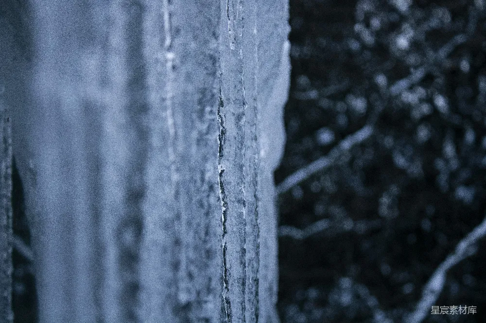 窗边悬挂着冰锥，背景是树木。