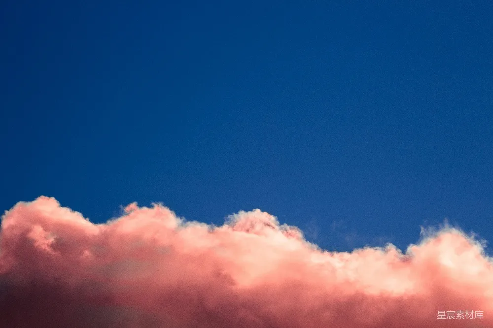 一架飞机在蓝天中穿行，白云呈粉色。