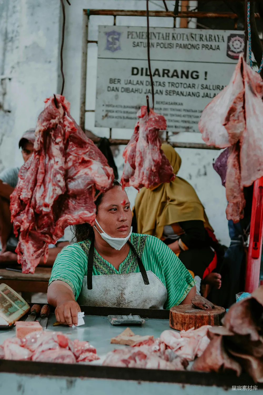 一个女人站在桌子旁边，桌子上摆满了肉。