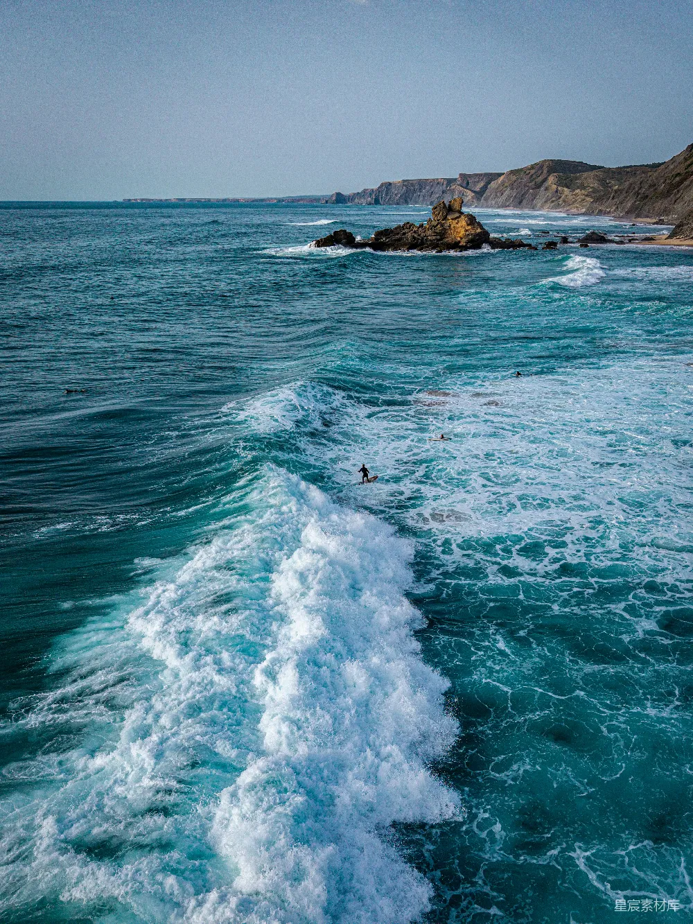 冲浪者在一片岩石海岸上驾驭着一个强大的波浪。