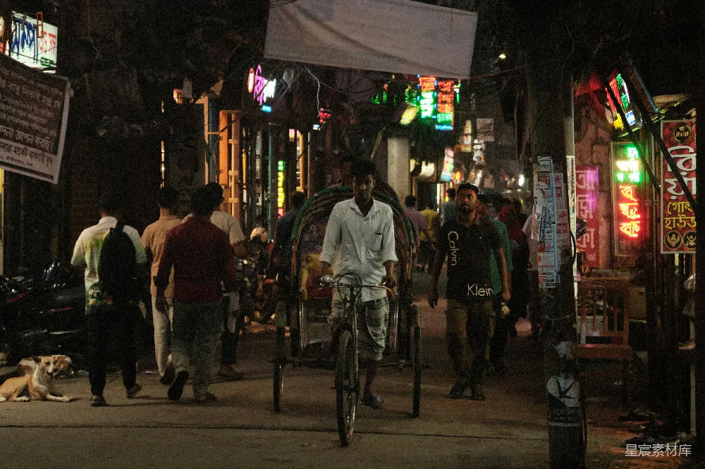 一个男子骑自行车在一条街道旁边遛狗