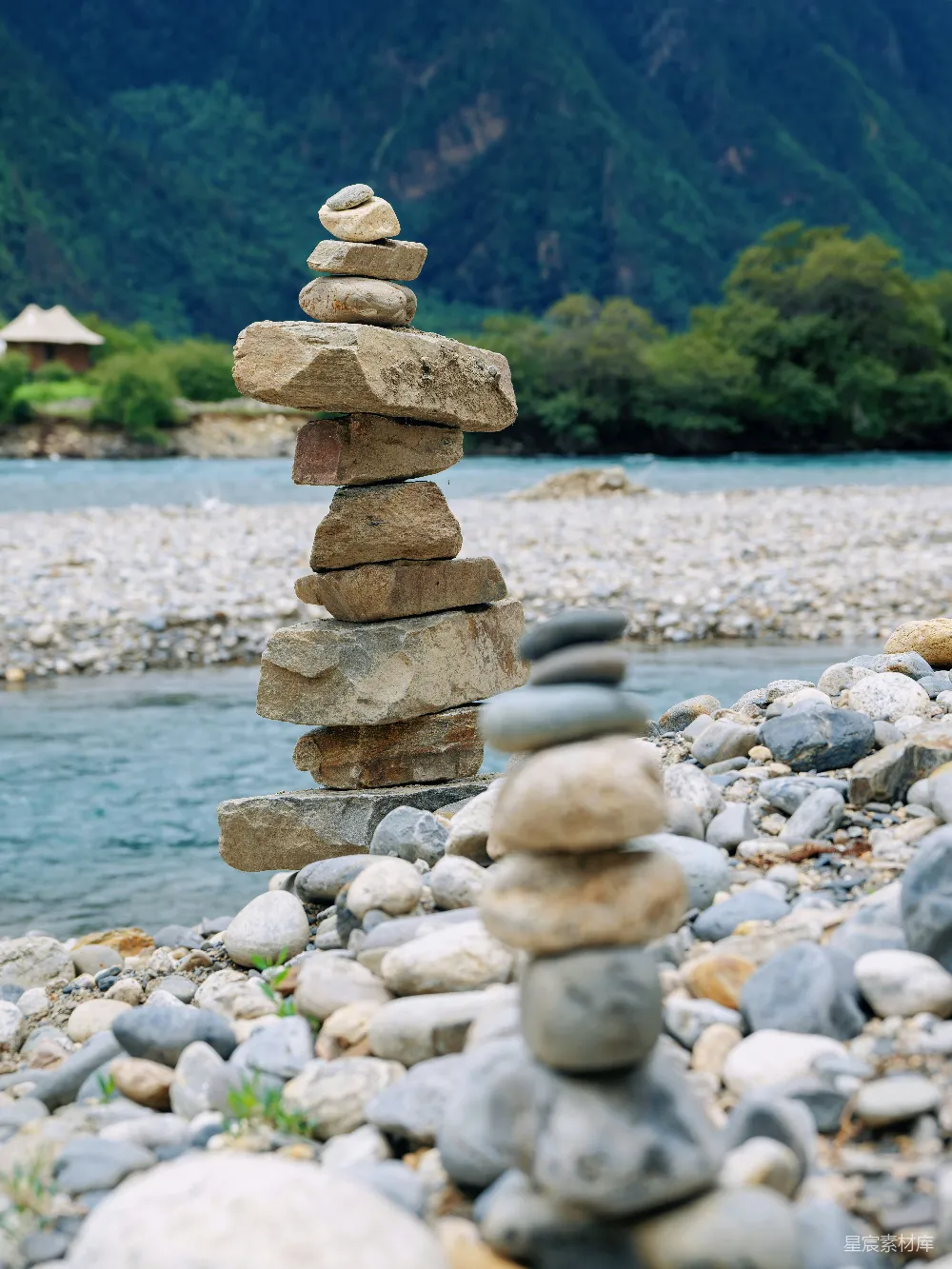 两岸山峦之间的两座平衡岩石堆栈旁的河流。