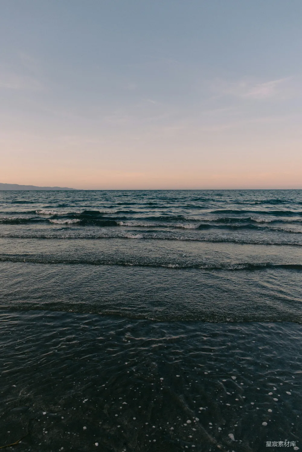 柔和的海浪在一片清澈、淡彩的天空下。