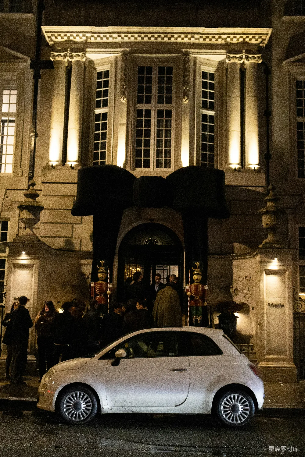 白色汽车停在建筑物外，有大型拱形入口的地方。
