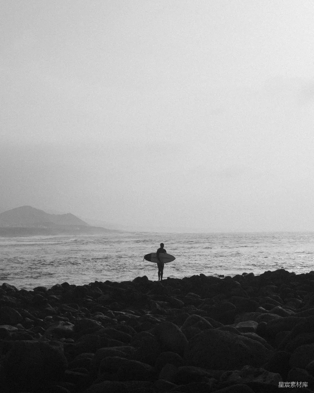 高清摄影  一个人在岩石海滩上拿着冲浪板
