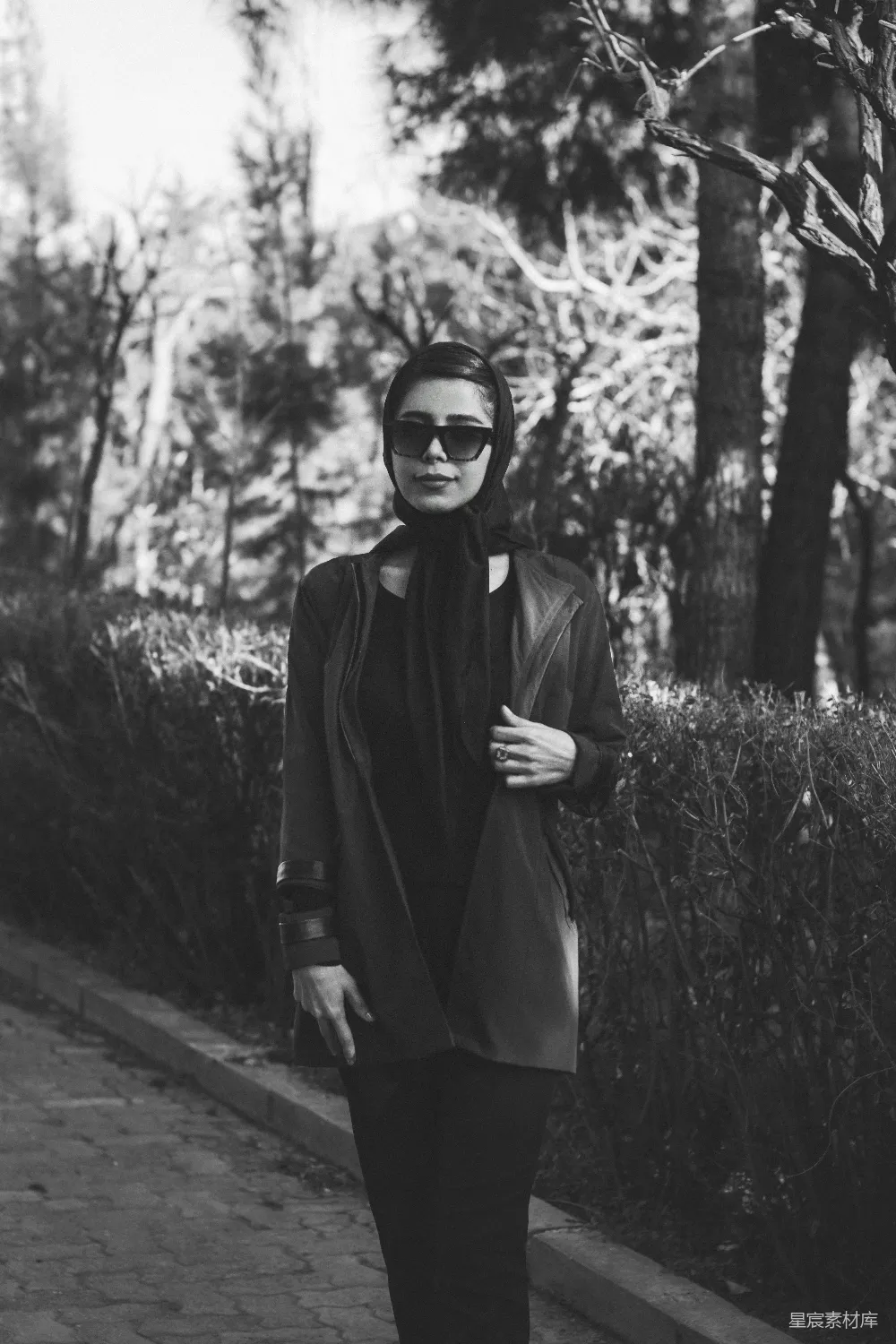 高清摄影  一张黑白照片中，一位女士正走在人行道上。