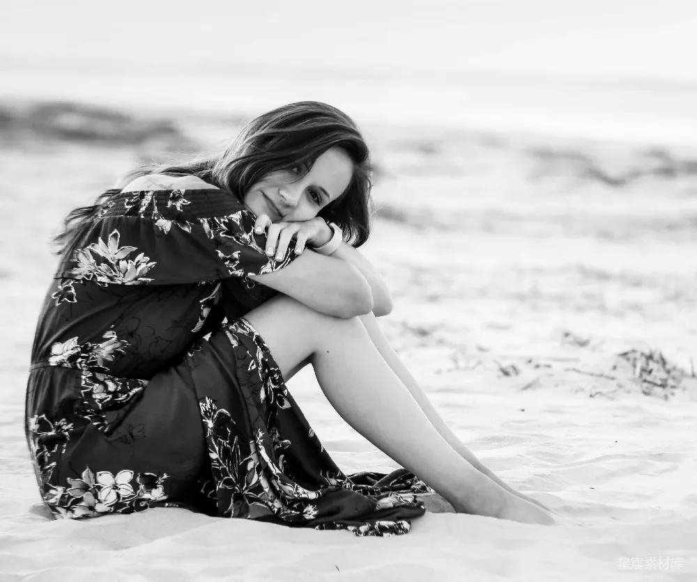高清摄影  穿着黑白花裙子的女人坐在海滩上