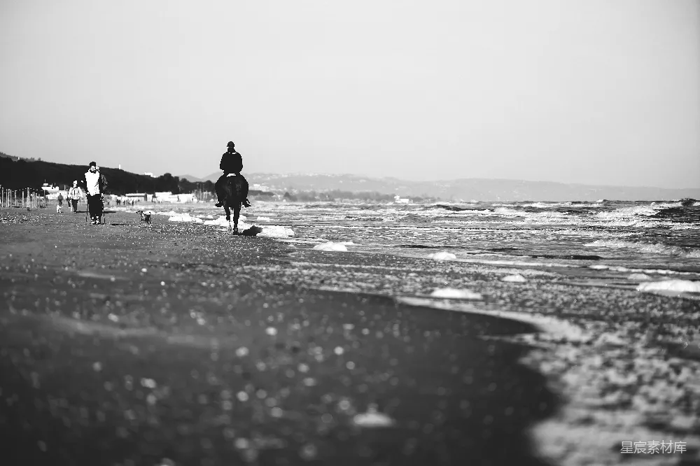 高清摄影  黑白照片中，一个人走在海滩上。