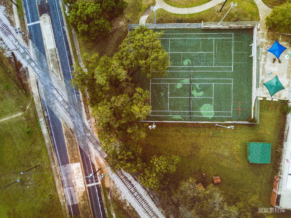 高清摄影  高角度拍摄的绿色草坪网球场，周围有树木、道路和铁路。