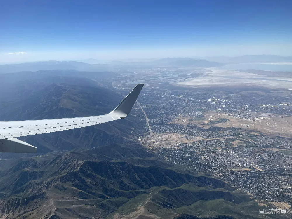 高清摄影  一架飞机在空中高飞，背景是山脉。
