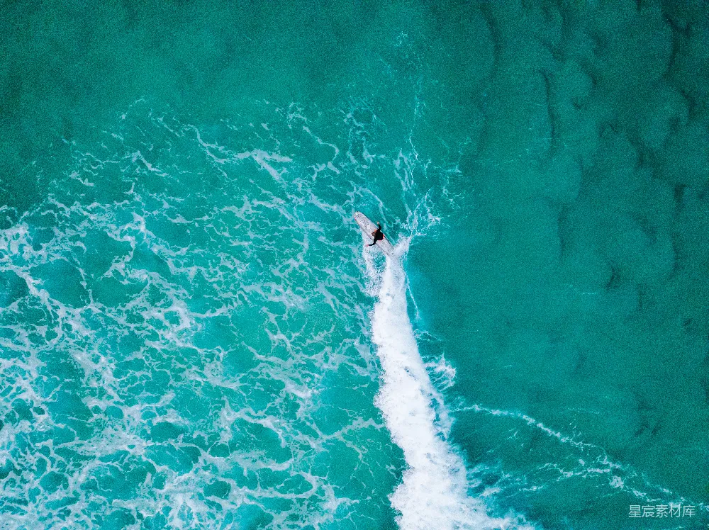 高清摄影  在海洋中，一个人骑着冲浪板在海浪上冲浪。