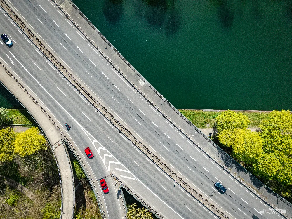 高清摄影  一座绿色河流旁的高速公路立交桥的空中俯瞰图。