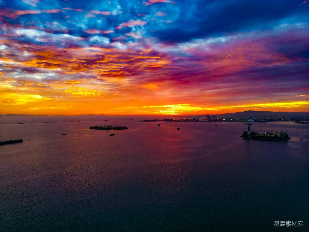 高清摄影  海洋上绚丽的夕阳，远处的城市灯光闪烁。