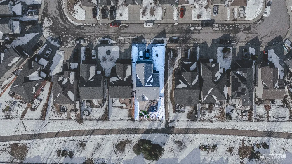 高清摄影  雪覆盖的住宅区航拍图，其中有一栋房子被突出显示。
