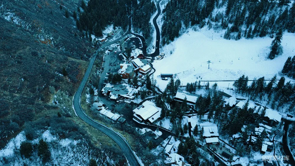 高清摄影  空中俯瞰一座被雪覆盖的山村，蜿蜒的小路蜿蜒其中。