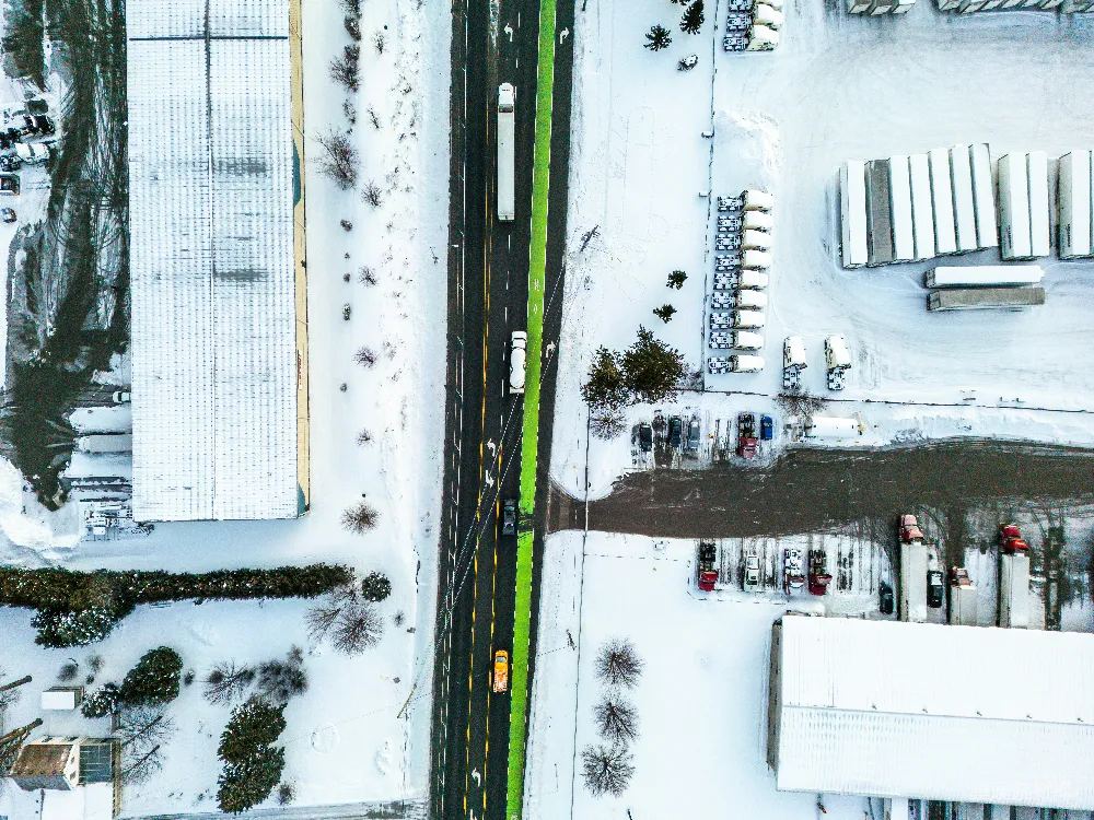 高清摄影  雪覆盖的周围环境中的一条高速公路的空中俯瞰图。