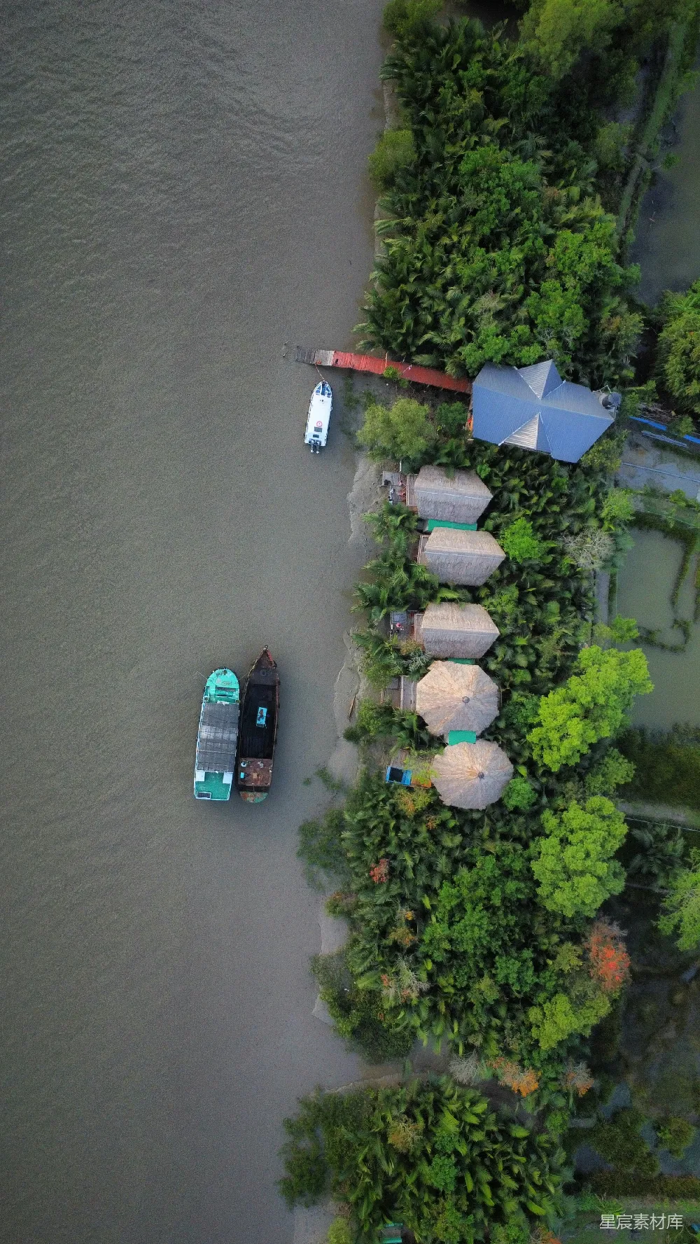 高清摄影 自然 河流的空中俯瞰图，可以看到河边停泊的船只和茅草屋顶的建筑。