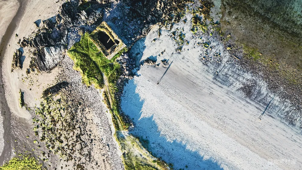 高清摄影  沙滩松软，海水清澈湛蓝，海岸岩石嶙峋，建筑废墟散落其中。