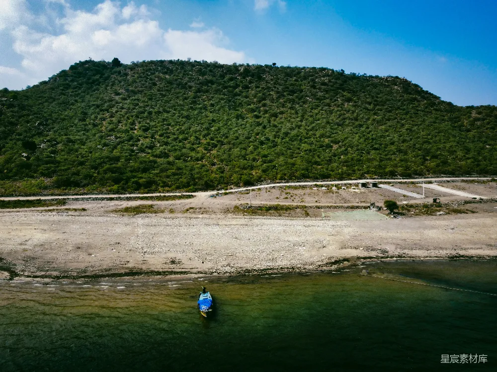 高清摄影  一个人在河里划着独木舟，背景中有一座小山。