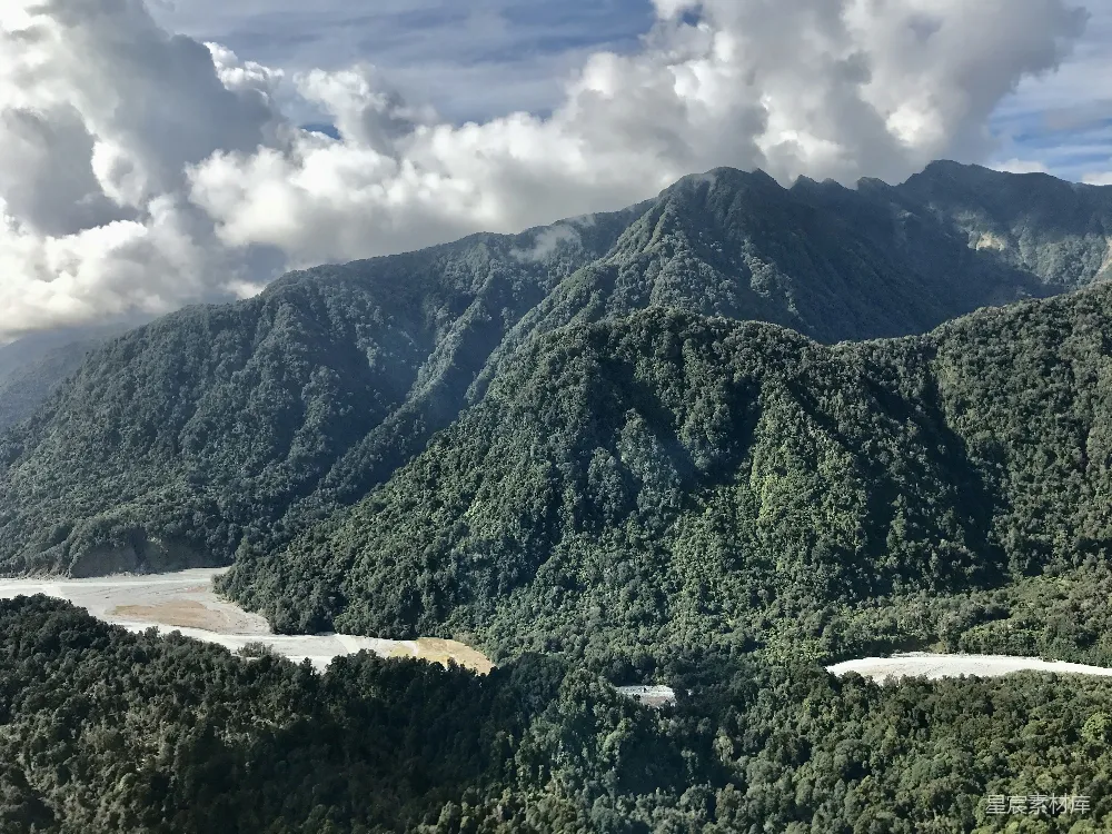 高清摄影 自然 白天，一片云层覆盖的天空下，水边有一座青山。
