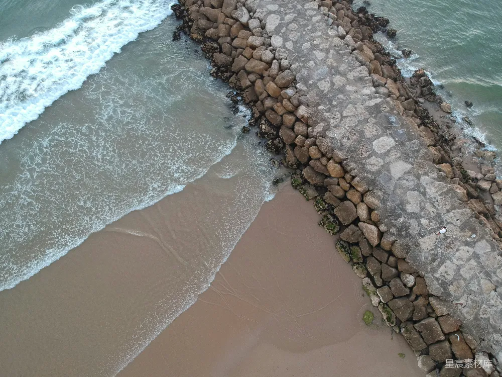 高清摄影  在海边有一堵石头墙，海浪正拍打着它。
