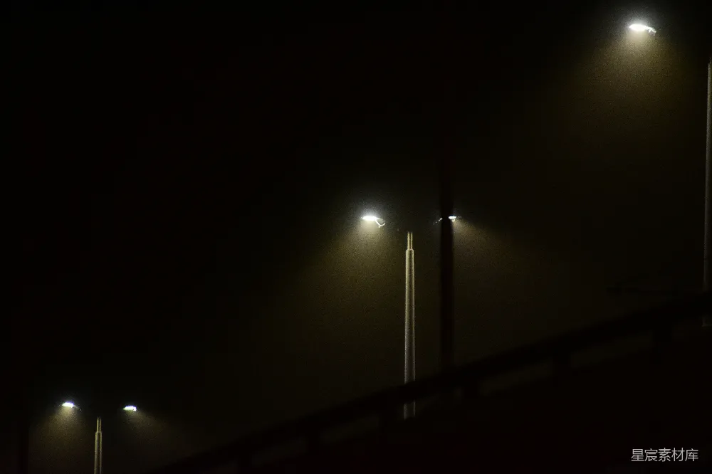 高清摄影  在一个雾蒙蒙的夜晚，一盏路灯在黑暗中亮着。