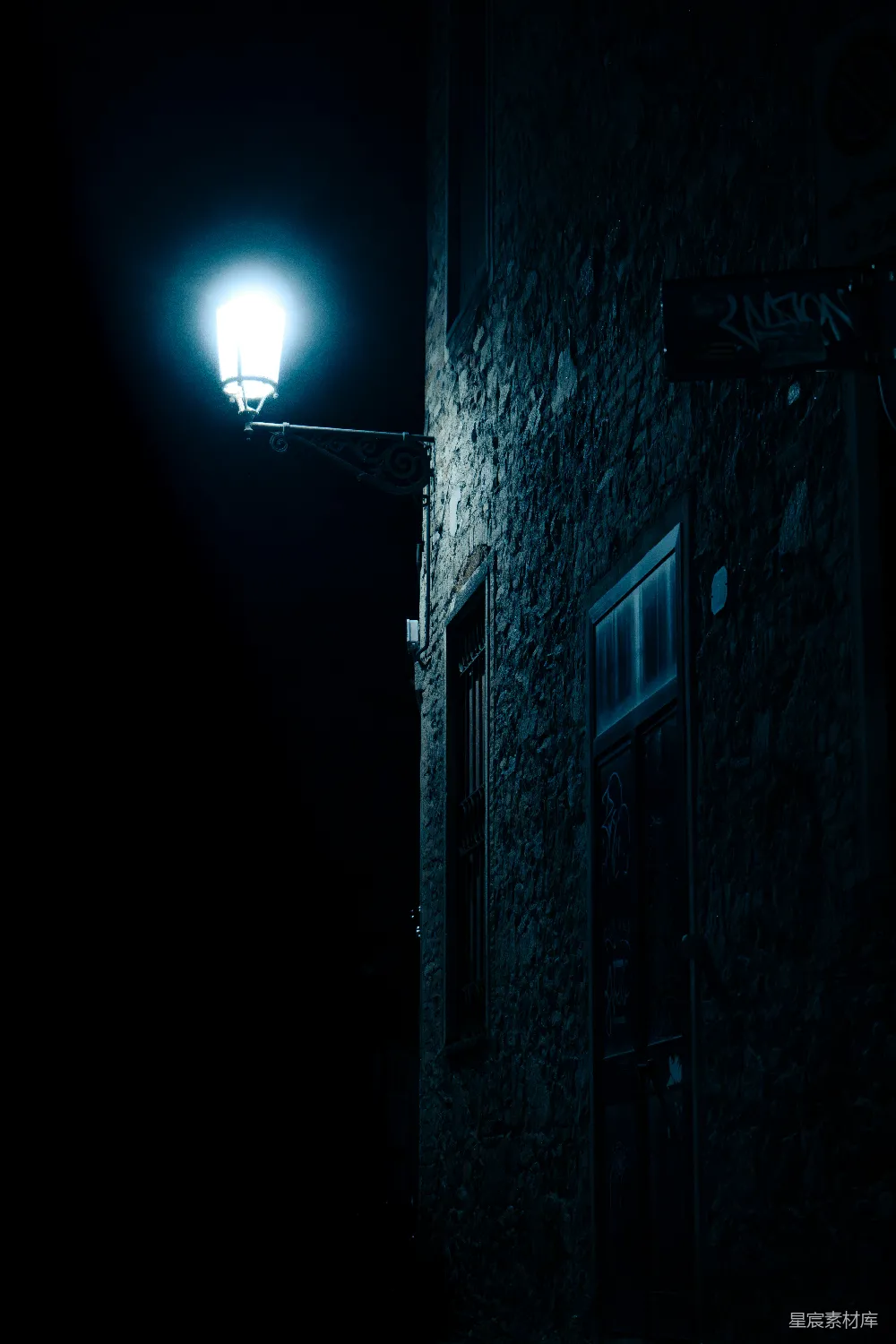 高清摄影  路灯在夜晚照亮了一座黑暗、纹理丰富的建筑物。