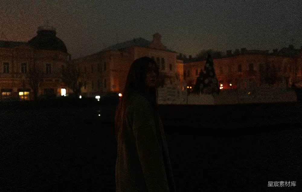 高清摄影  一个女人站在夜晚的建筑物前。
