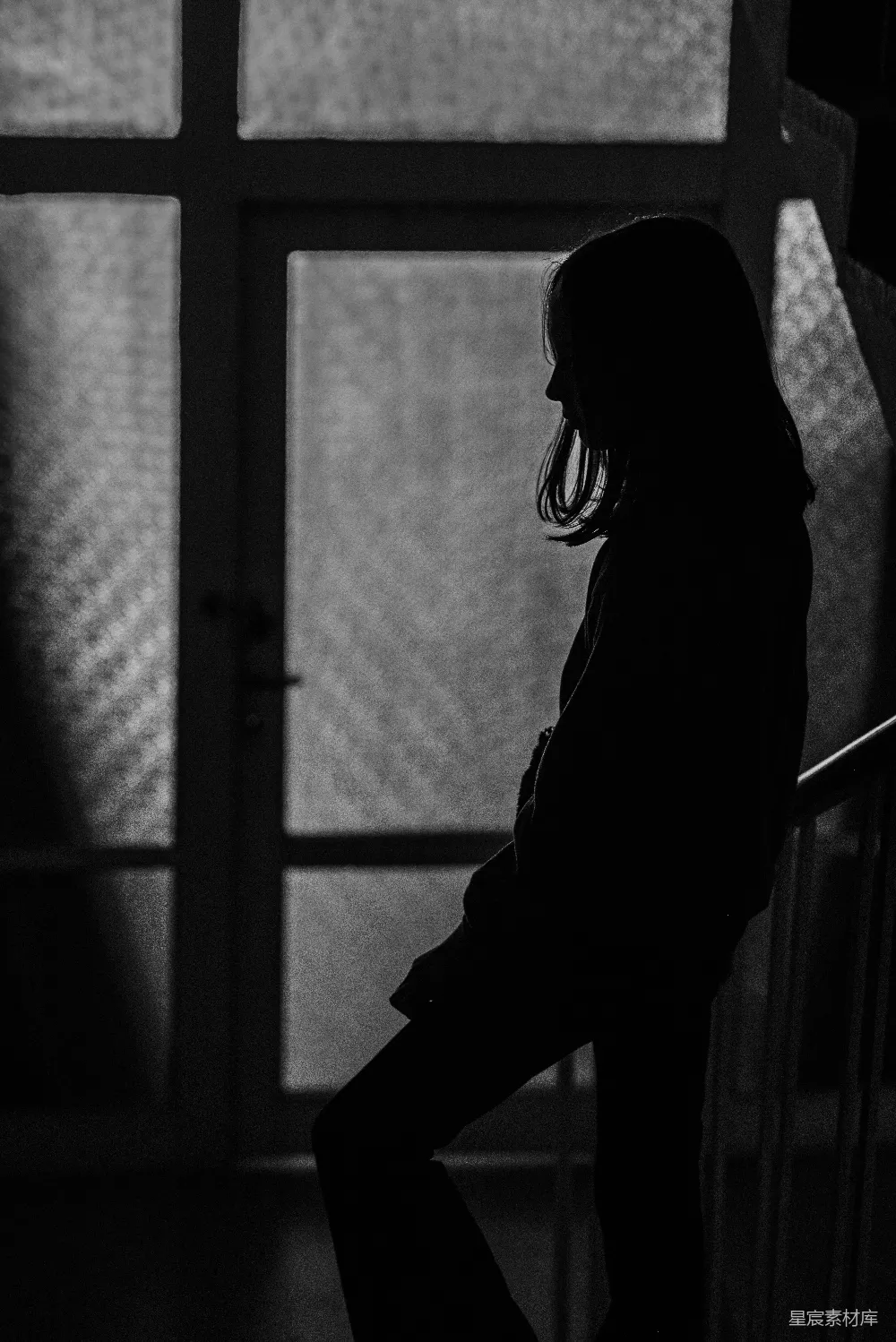 高清摄影  一个女人站在楼梯旁的窗户边。