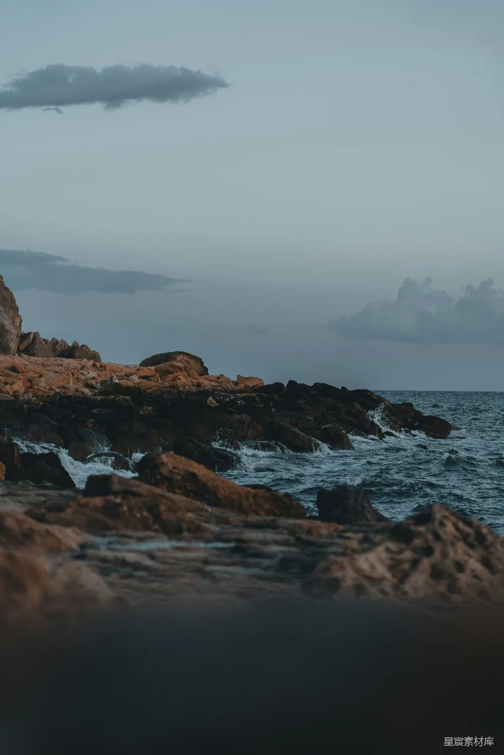 高清摄影  一个人站在岩石海岸边，面对着海洋。