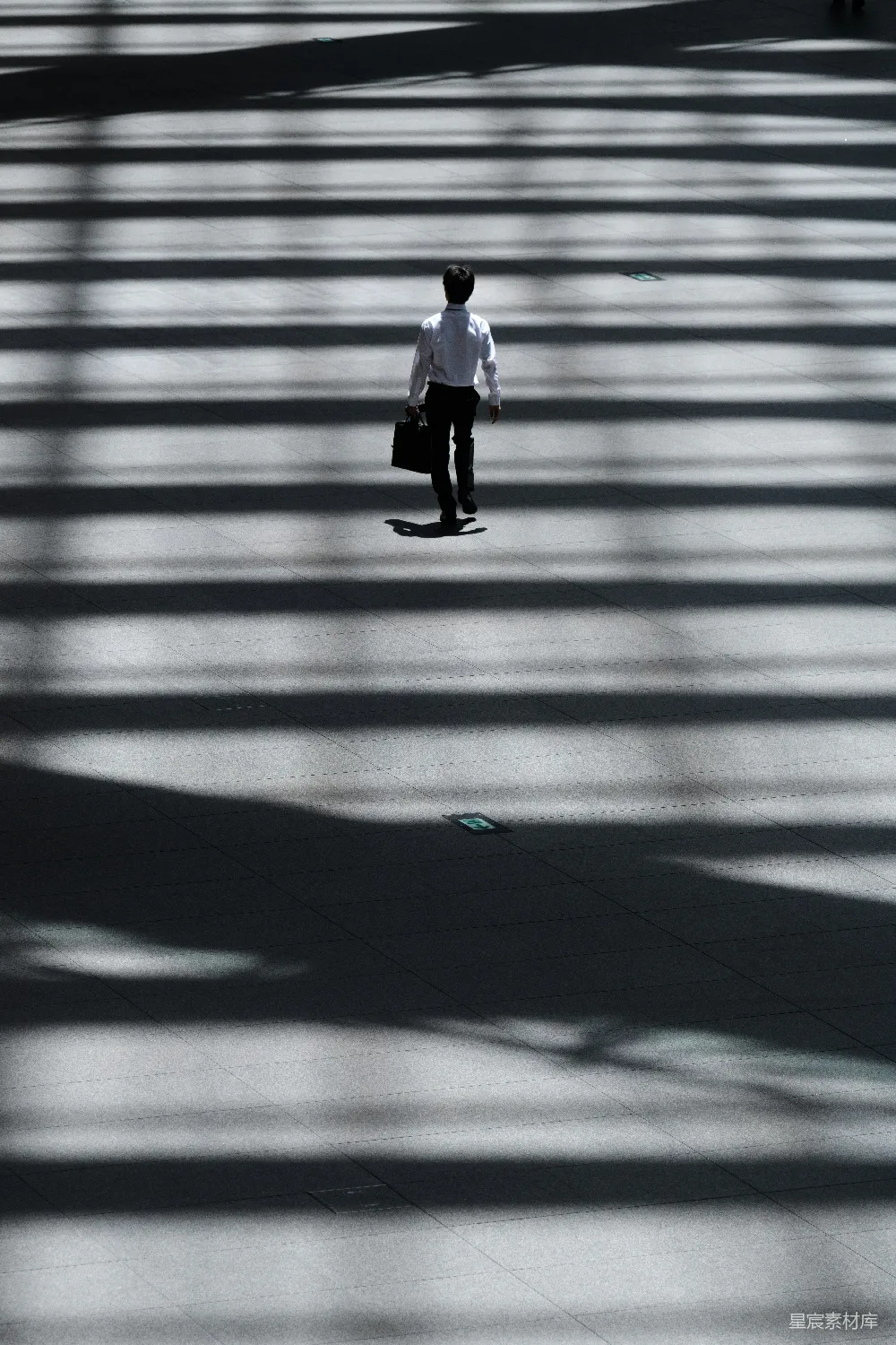 高清摄影  一个男人拿着笔记本电脑包走在街上。
