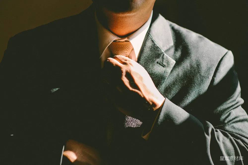 高清摄影  一个穿黑色西装的男人正在松开他的领带。