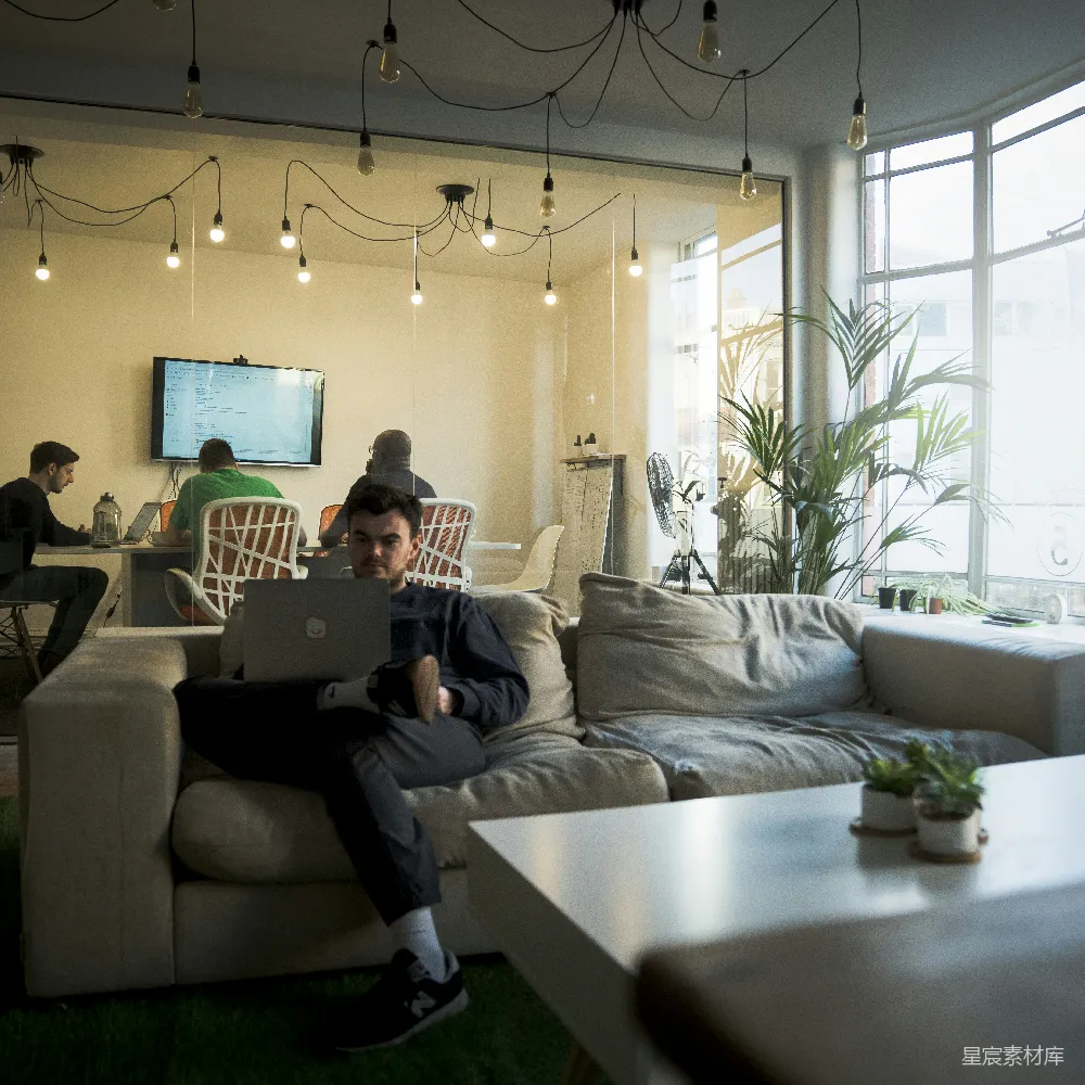 高清摄影  穿着黑色T恤的男人坐在沙发上使用MacBook电脑。