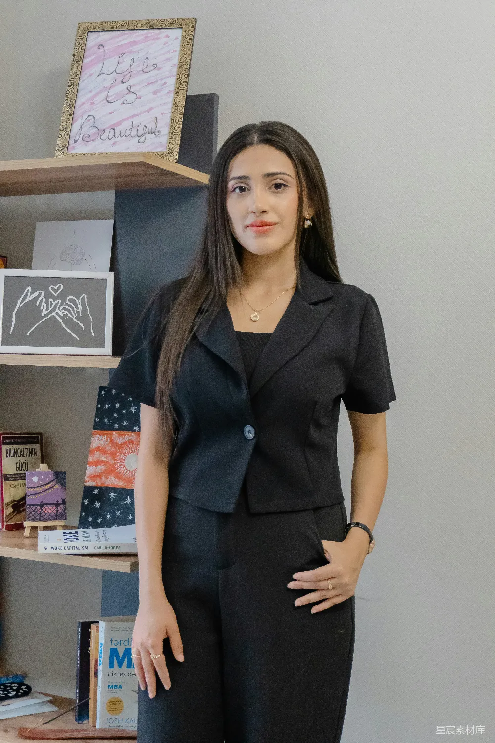 高清摄影  一位穿着黑色西装的女士站在书架旁。