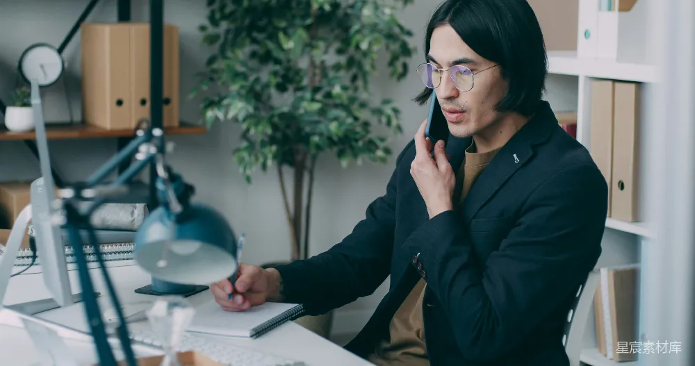 高清摄影  一个男人坐在桌子旁打电话。