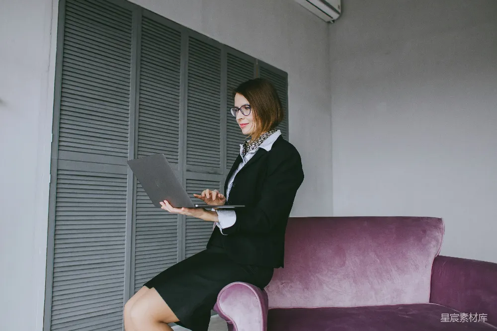 高清摄影  一个女人坐在沙发上使用笔记本电脑。